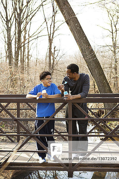 Happy father and son eating ice slush while standing on footbridge