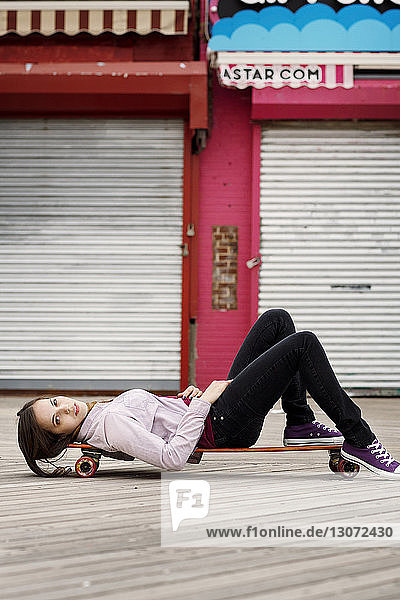 Porträt einer auf einem Skateboard liegenden Frau