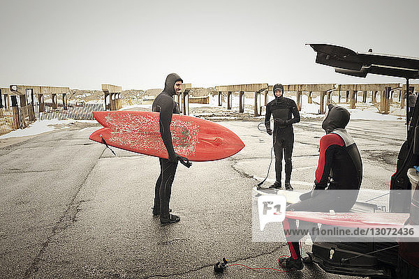 Friends in wetsuits preparing for surfing