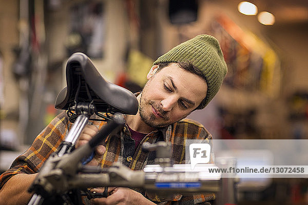 Man repairing bicycle while standing in workshop
