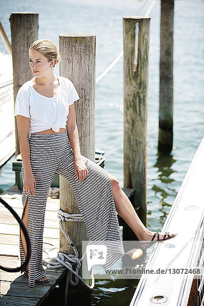 Woman looking away while standing on jetty at harbor