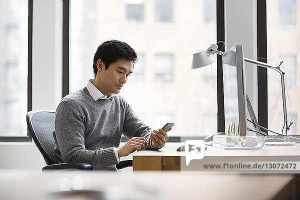 Mann benutzt Smartphone bei der Arbeit im Büro