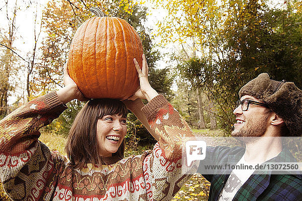 Mann hilft Frau beim Tragen eines Halloween-Kürbisses