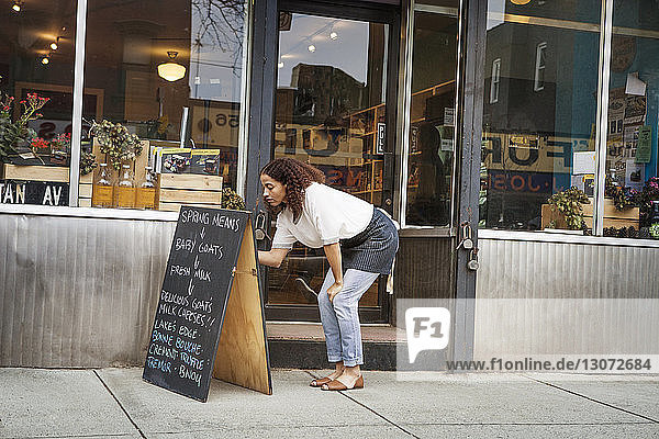 Frau schreibt auf Tafel vor Laden