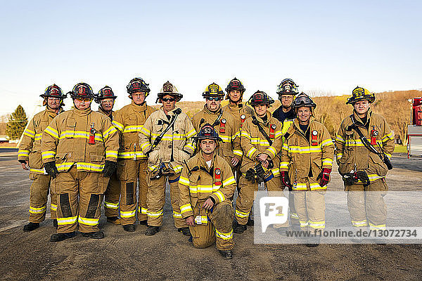 Porträt von Feuerwehrleuten  die in der Feuerwache vor klarem Himmel stehen