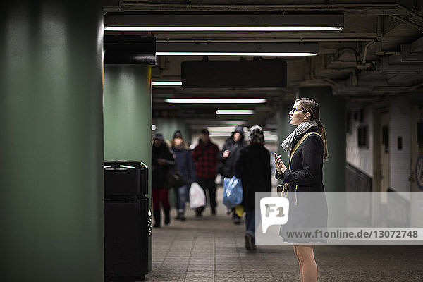 Side view of woman standing at subway station