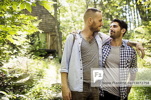 Homosexual couple looking at each other while walking in forest