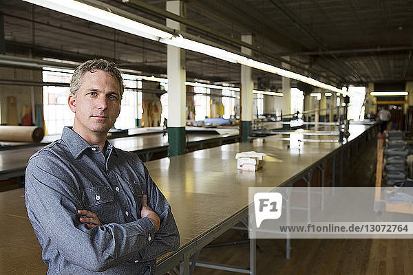 Portrait of businessman standing by table in factory