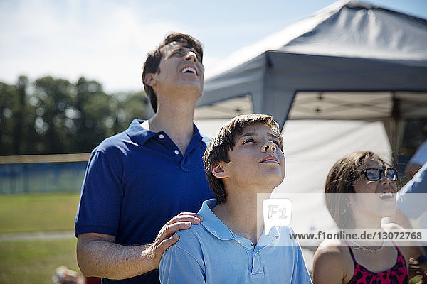 Erwachsener Mann und Kinder schauen auf  während sie im Park stehen
