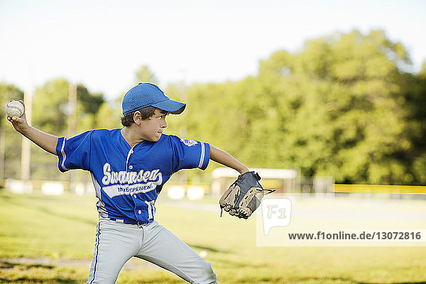 Baseball player throwing ball against sky