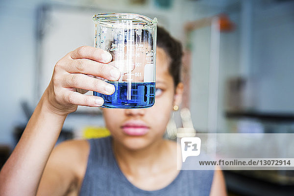 Schüler untersucht Chemikalie im Becherglas im High-School-Labor
