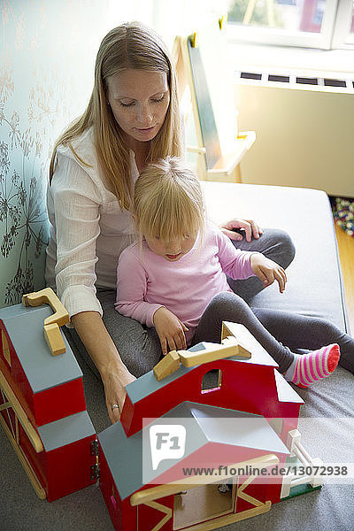 Schrägansicht von Frau und Tochter beim Spielen mit der Modellscheune zu Hause