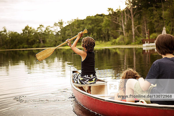 Junge rudert  während er mit seinen Geschwistern im Kanu sitzt
