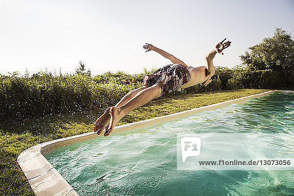 Mann springt in Schwimmbad gegen klaren Himmel