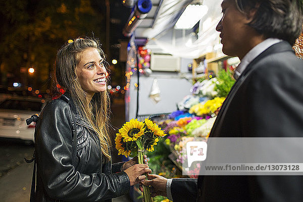 Mann schenkt seiner Freundin Sonnenblumen  während er am Blumenladen steht