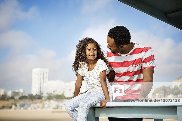 Vater sieht Mädchen an  während er am Pier gegen den Himmel steht