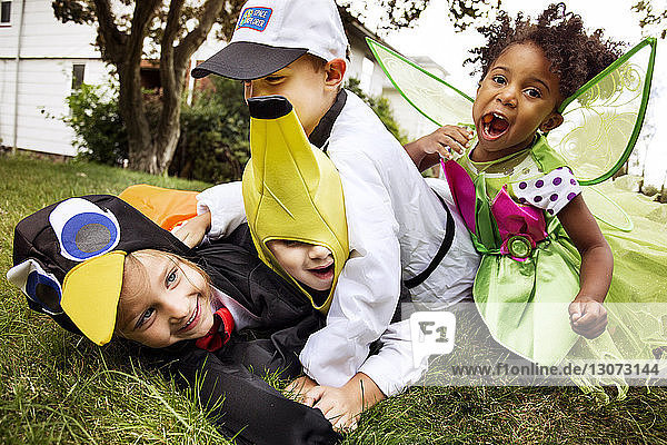 Fröhliche Kinder in Halloween-Kostümen spielen auf Rasen