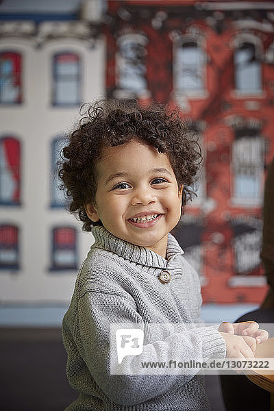 Portrait of smiling cute boy sitting at table in preschool