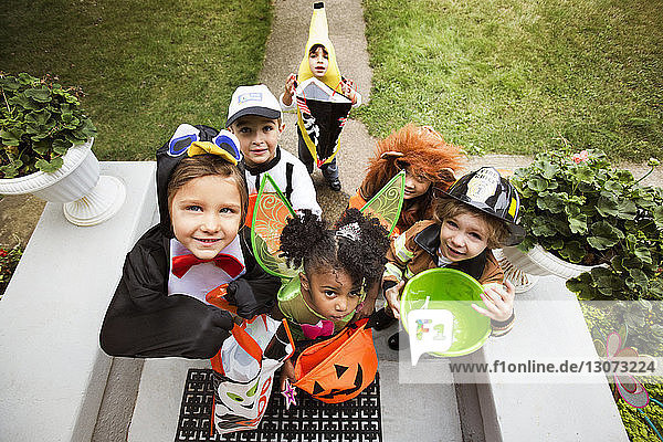 Fröhliche Kinder in Halloween-Kostümen  die während einer Süßes-oder-Saures-Tour vor der Tür stehen