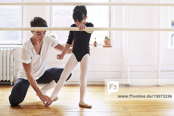 Männlicher Ballettlehrer unterrichtet Ballerina im Studio
