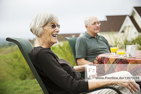 Ältere Frau schaut weg  während sie mit ihrem Mann am Tisch im Rasen sitzt