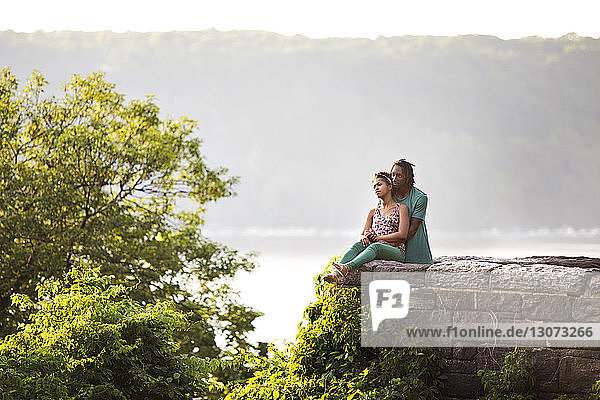 Paar entspannt sich durch Stützmauer am Park gegen Berg