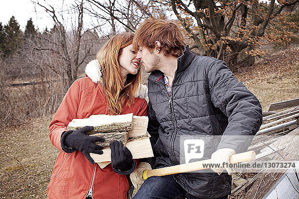 Küssende Paare beim Brennholzschneiden