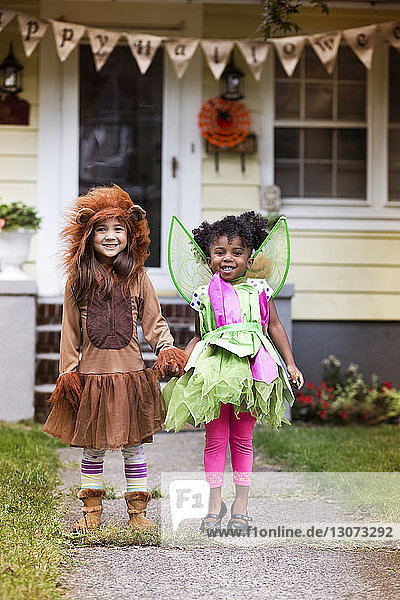 Porträt von lächelnden Mädchen in Halloween-Kostüm  die vor dem Haus im Hof stehen