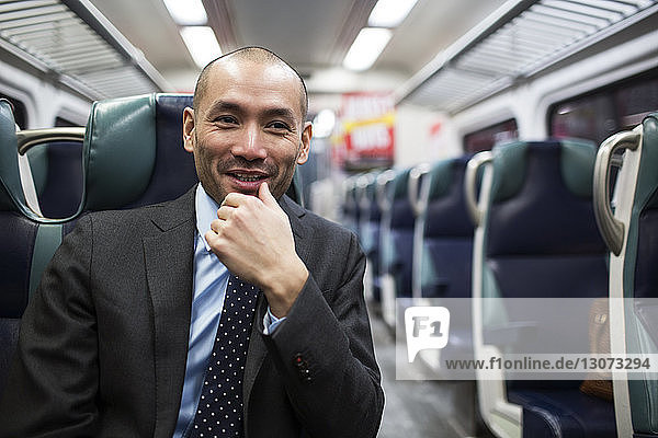 Happy businessman looking away while traveling in subway train