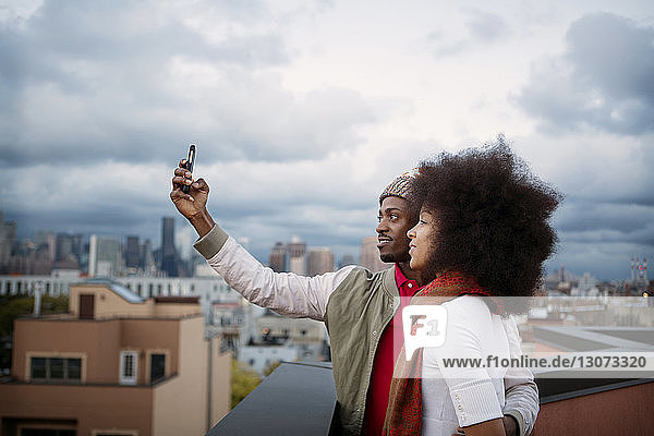 Couple taking selfie while standing on building terrace