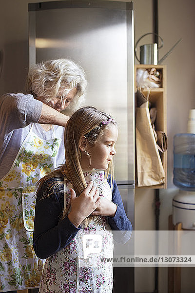 Frau bindet Enkelin die Schürze zu  während sie in der Küche steht