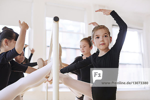 Confident ballerinas leaning on rod at studio