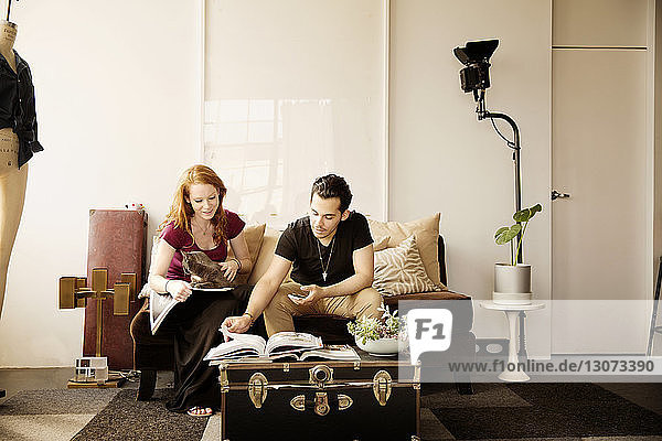 Paar liest Buch  während es zu Hause auf dem Sofa sitzt