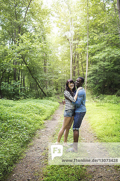 Glückliches Paar umarmt sich im Wald stehend