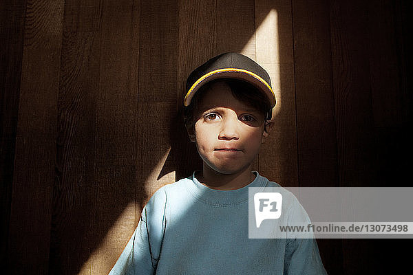 Porträt eines an einer Holzwand stehenden Jungen