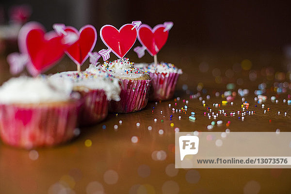 Cupcakes decorated with heart shape sticks on wooden table