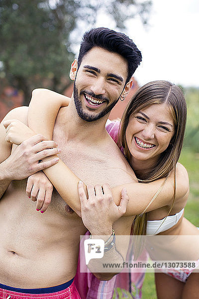 Portrait of cheerful couple in swimwear standing at yard