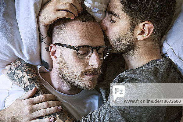Hochwinkel-Nahaufnahme eines liebenden homosexuellen Paares  das zu Hause auf dem Bett liegt