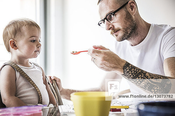 Wütender Vater füttert Tochter am Frühstückstisch