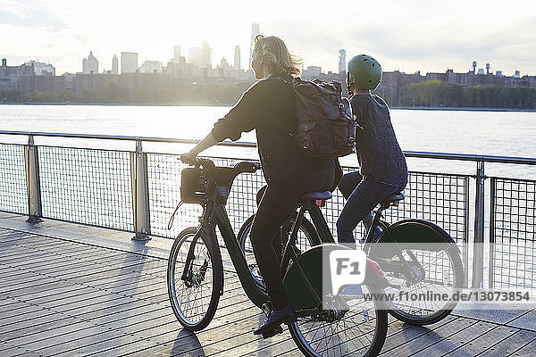 Freunde fahren Fahrrad auf der Promenade am Fluss