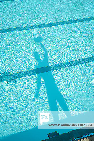 Schatten eines Mannes mit Kurzhanteln im Schwimmbad gesehen