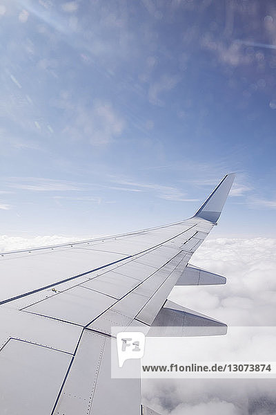 Ausschnittsbild eines Flugzeugflügels über Wolken gegen den Himmel
