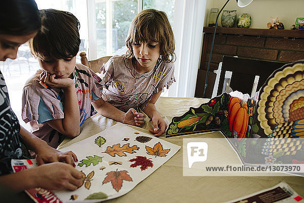 Girl with siblings removing leaves labels at table