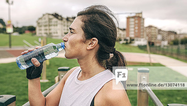 Frau trinkt Wasser beim Sport im Park