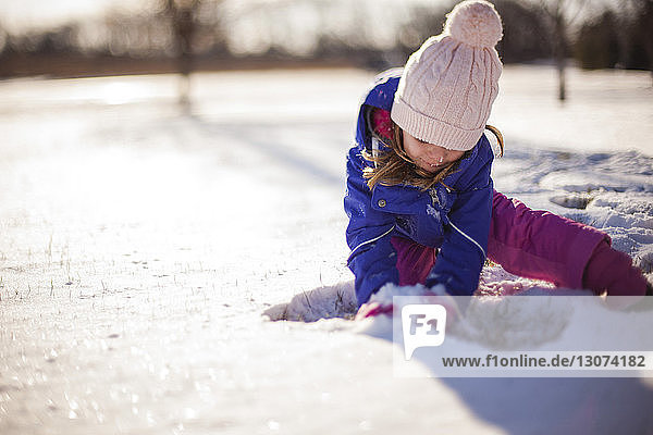 Mädchen spielt mit Schnee an einem sonnigen Tag
