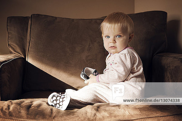 Porträt eines kleinen Mädchens  das zu Hause auf einem Sessel sitzt