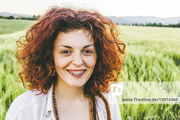 Bildnis einer lächelnden Frau mit Rothaarigen auf einem Bauernhof gegen den Himmel stehend
