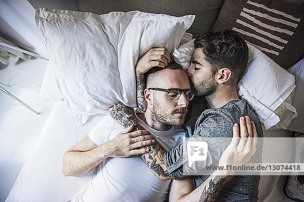 Hochwinkelaufnahme eines liebenden homosexuellen Paares  das zu Hause auf dem Bett liegt