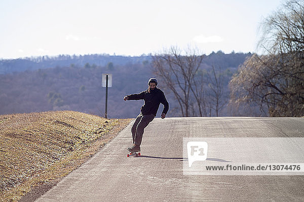 Skateboardfahren in voller Länge auf der Landstraße während des Urlaubs