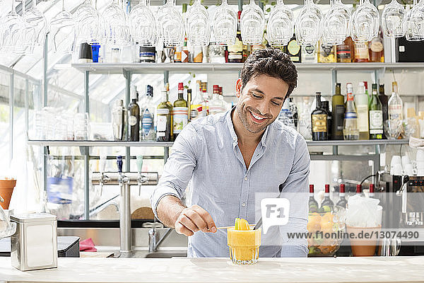 Fröhlicher Barkeeper bereitet Cocktail im Restaurant zu